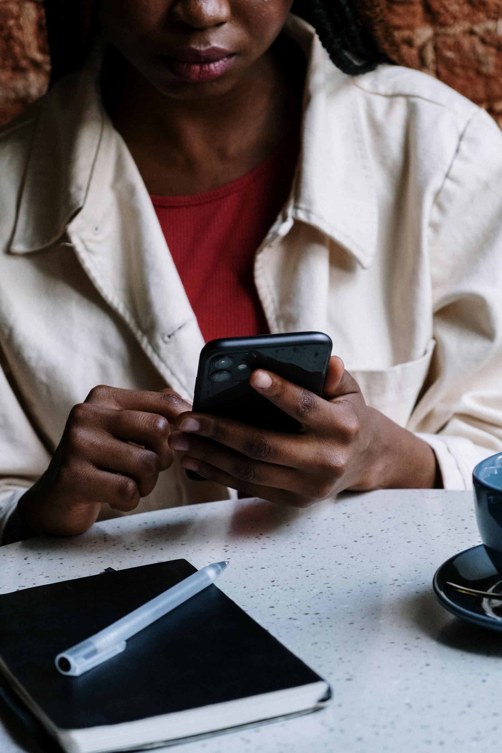 An African American woman using her smartphone at a cafe, focusing on technology and communication.